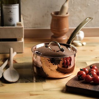 Handmade copper saucepan with a tin-lined interior, hammered finish, and brass handle. Includes a matching lid, ideal for gourmet cooking and precise heat control.