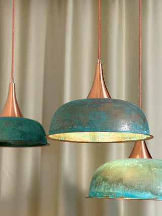 Handmade hammered copper pendant light with a green patina finish, complete with a textile cord and solid copper base, available in multiple sizes.