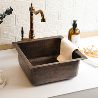 Handmade dark copper square kitchen vessel sink with a hammered finish, farmhouse style, and included drain cap, suitable for undermount or vessel installation.