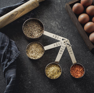 Set of four handmade solid copper measuring cups with a tin-lined interior, engraved measurements in cups and milliliters, and a stackable design.