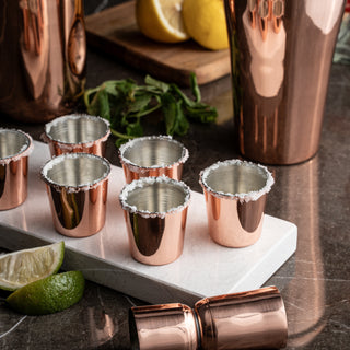 Set of six handcrafted copper shot glasses with a polished finish and food-safe tin lining, ideal for serving tequila, vodka, or spirits.